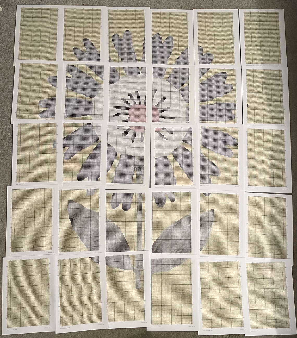 An image of 30 cross stitch pattern pages laid out on the floor