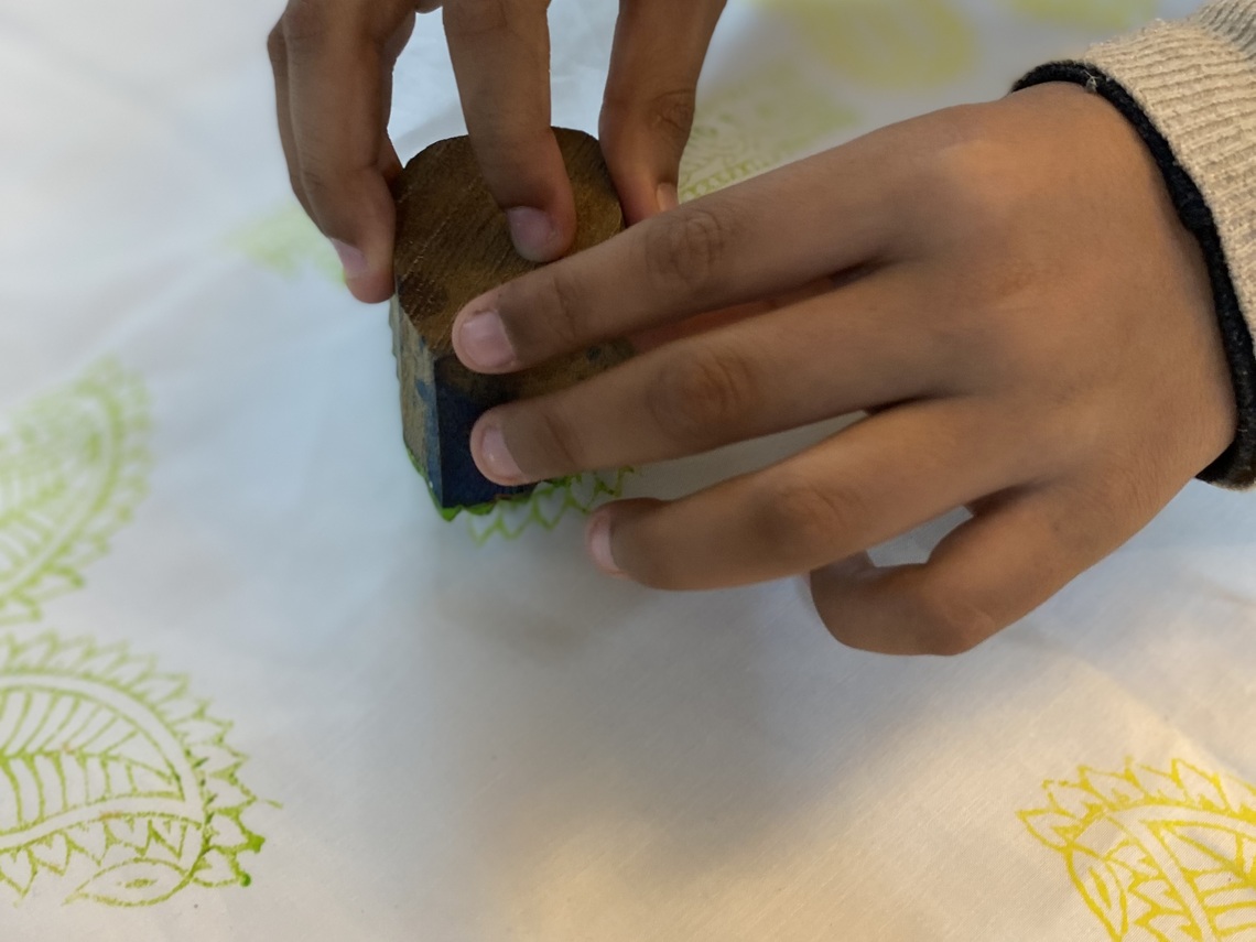 A child’s hand block printing on white fabric