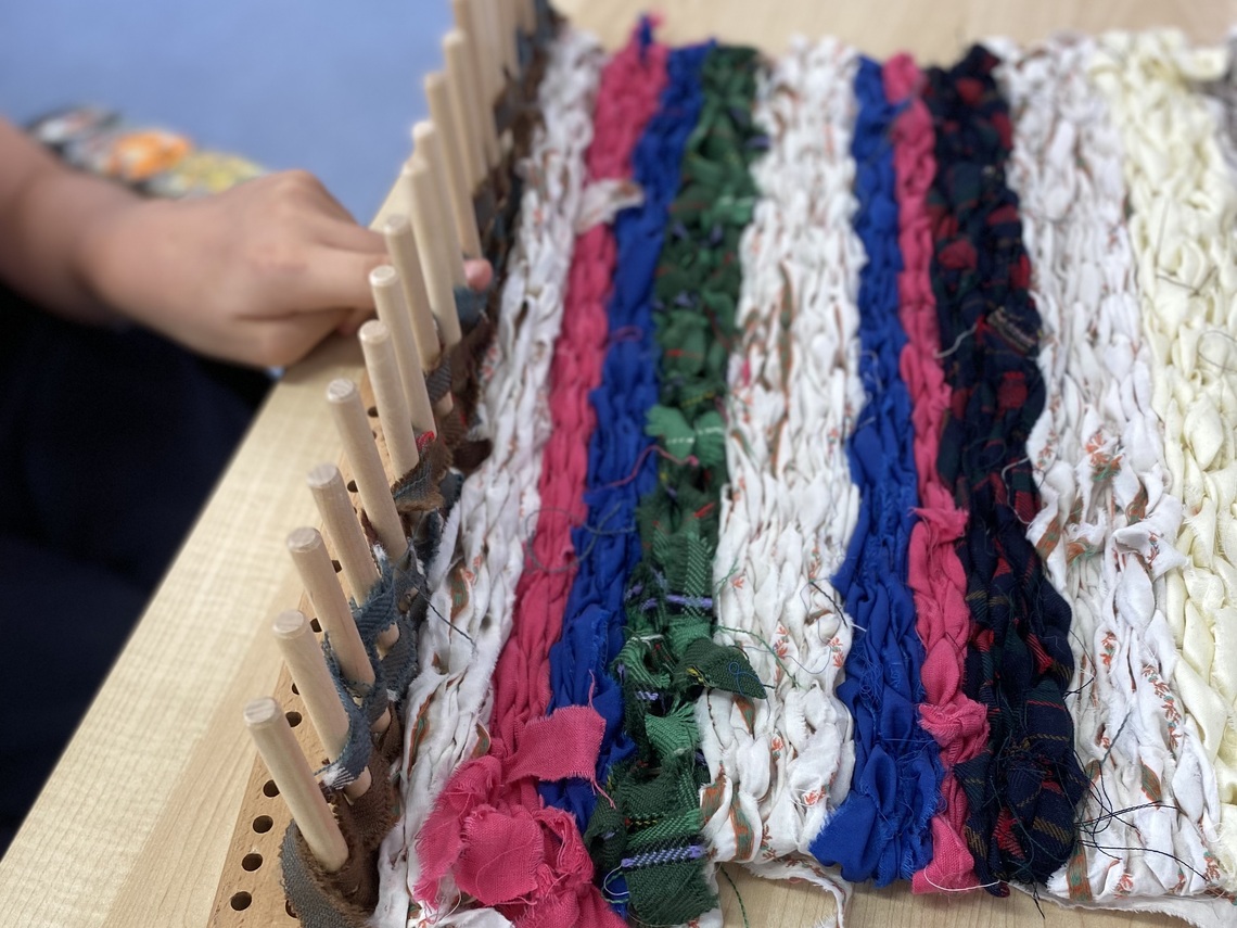 A hand weaving on a Peg loom 