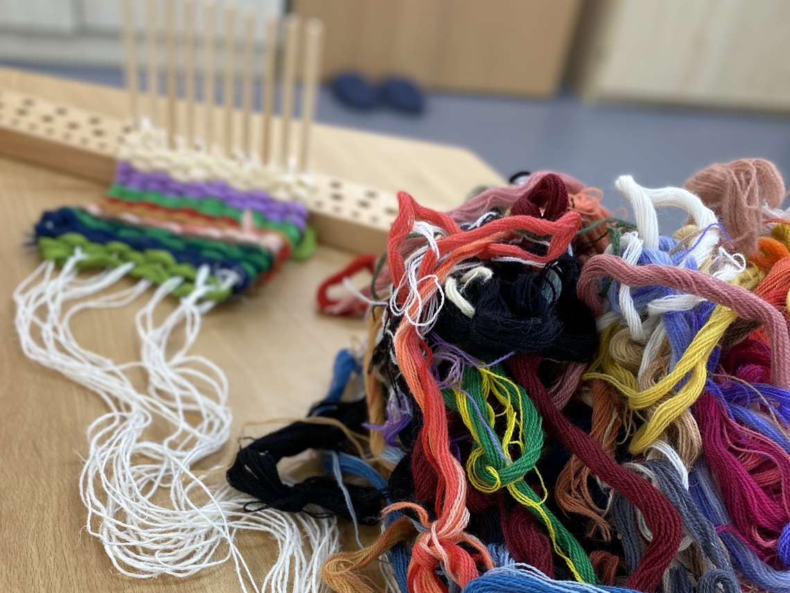 A peg loom set up with colourful yarns