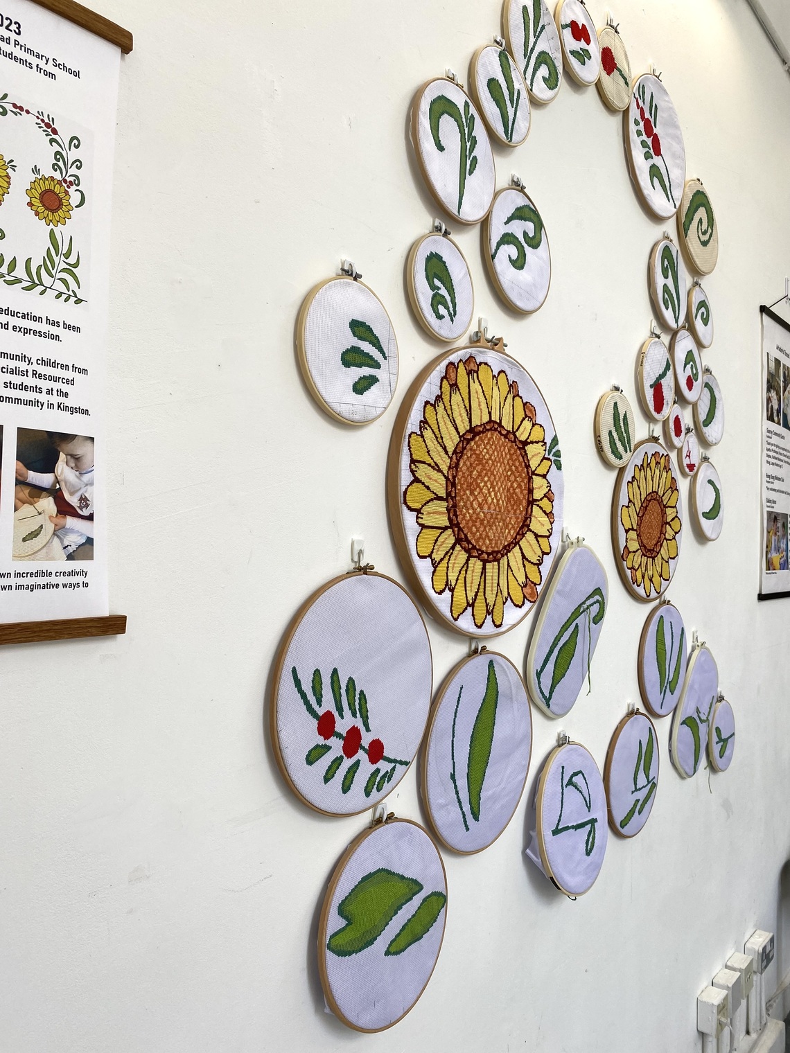 A wall display of cross stitch embroideries in hoops