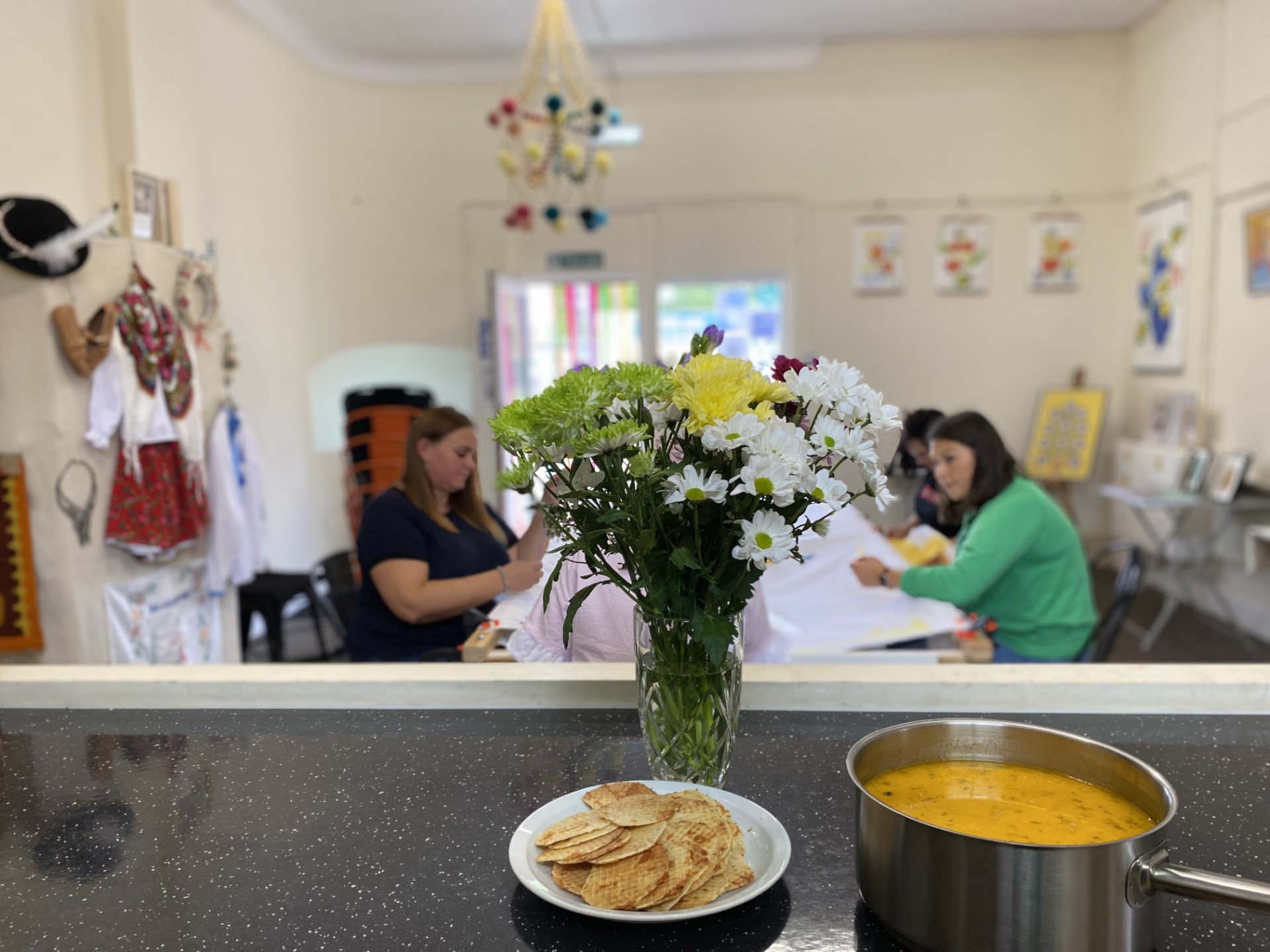 A group stitching around a table in the community kitchen