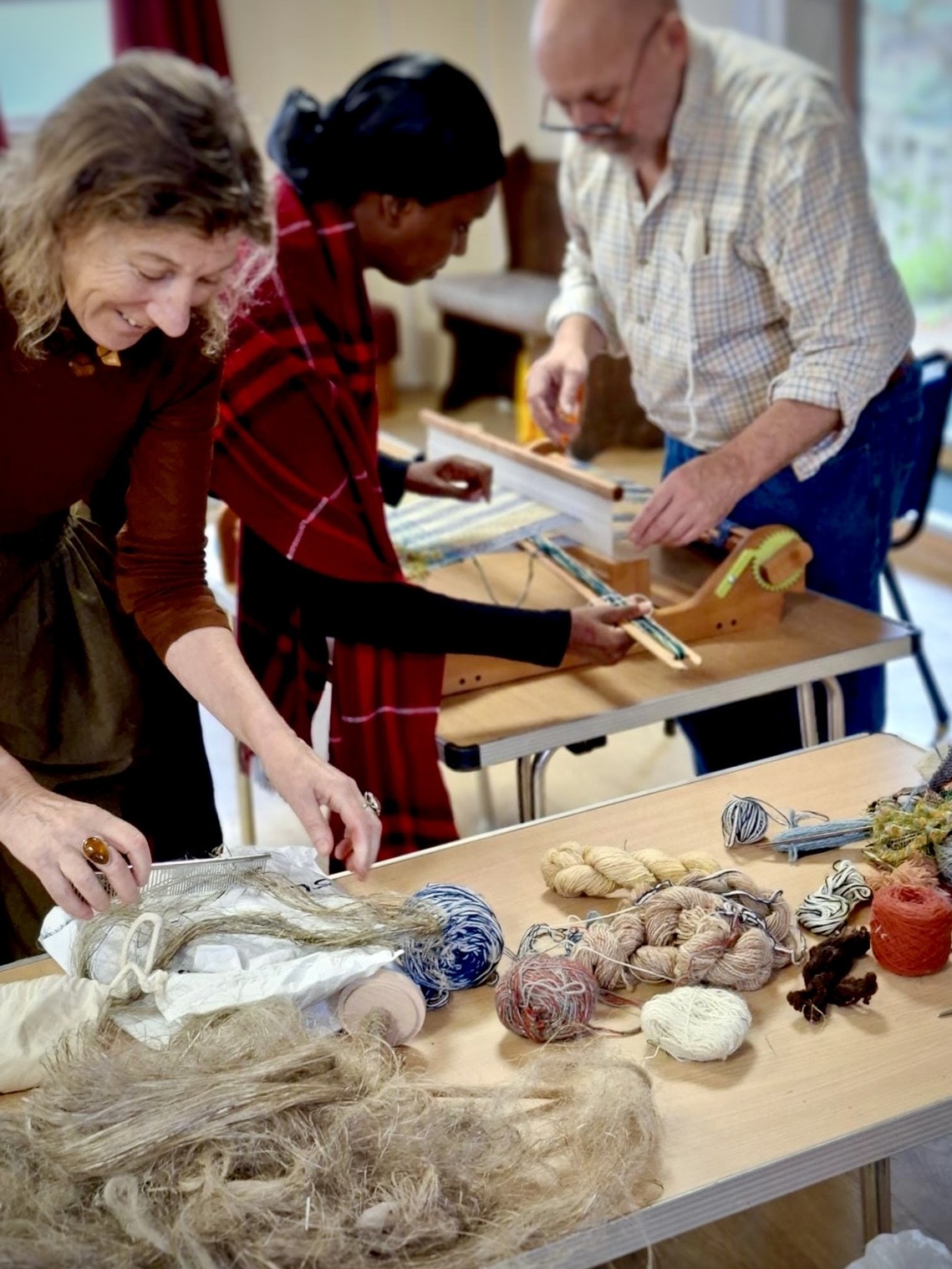 Participants trying different weaving techniques on table  looms
